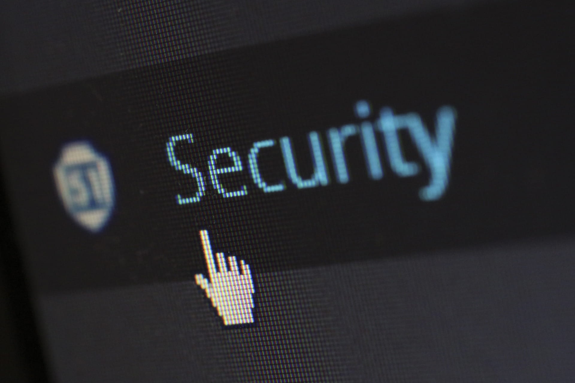 Texto “Security” borroso en pantalla con icono de escudo a la izquierda, fondo oscuro y píxeles visibles. Seguro de ciberseguridad