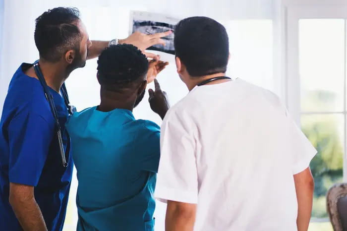 Médicos revisan una radiografía en un hospital, de espaldas, con bata y estetoscopio. Seguro de Responsabilidad Civil Médica, daños a terceros por mala praxis.